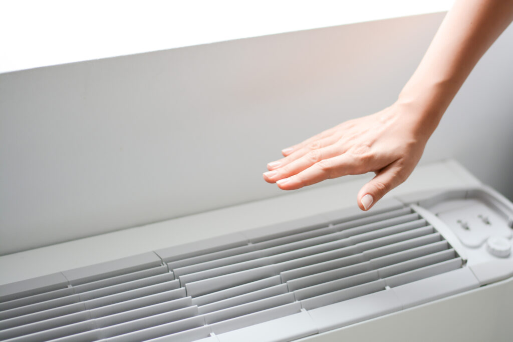 A hand hovering over ductless mini-split vent, feeling for air.